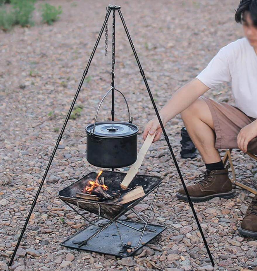 {{Camping Gear {{ Hiking Gear }} }} - {{Tac Treasure Shop }} {{ Tripod  with hanging pot over campfire}} {{ Young ma attending fire }}